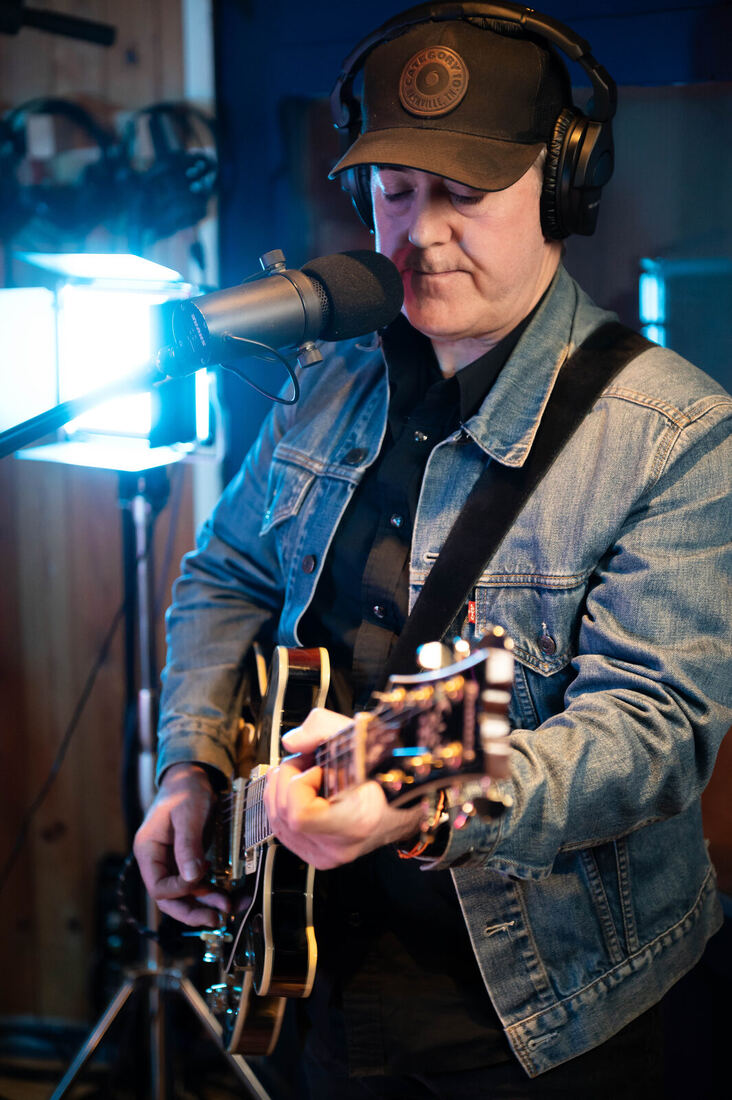 Dan singing and playing guitar in the studio